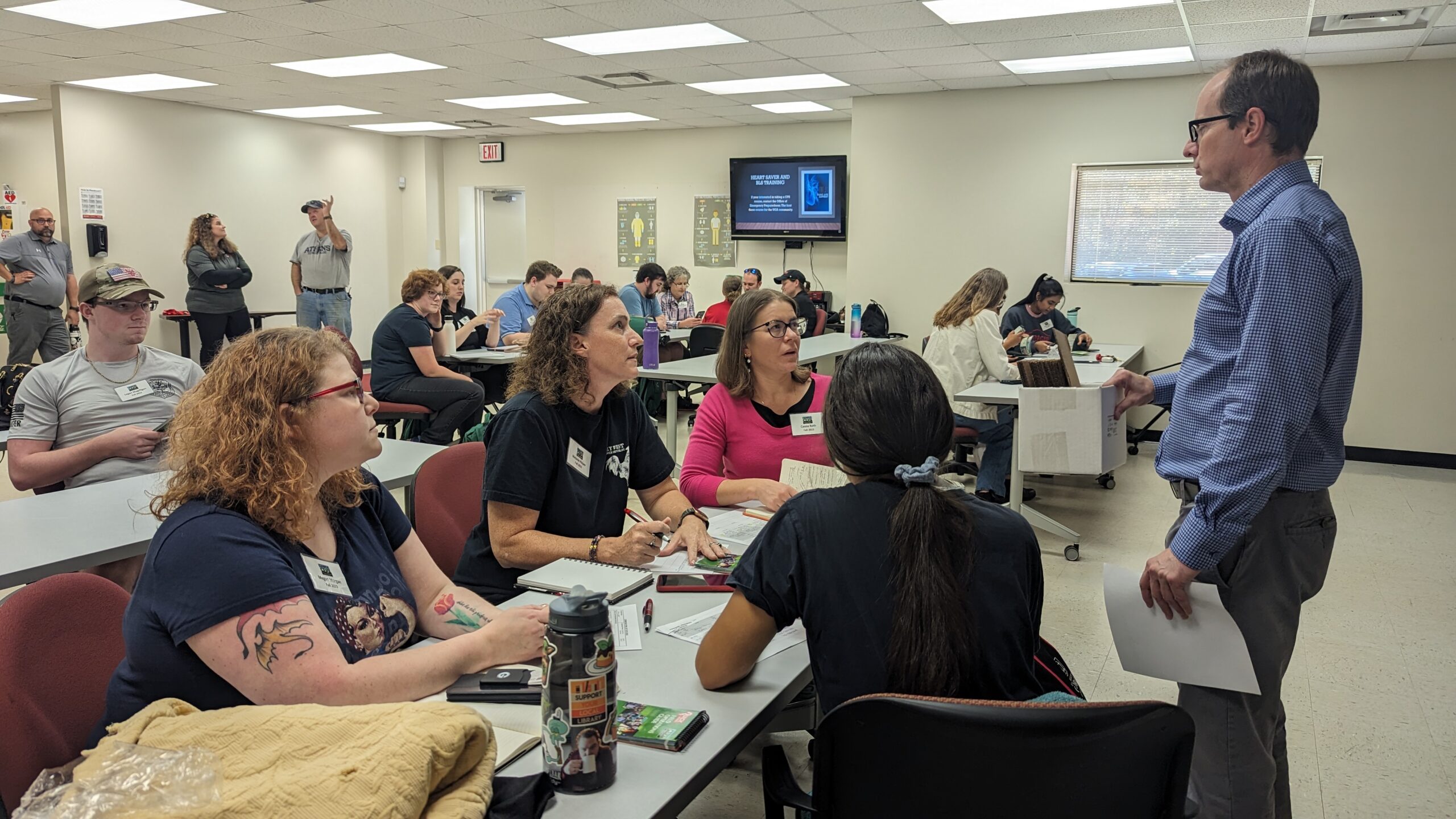 John Newton standing in a large room talking with members of the community response team during a training exercise