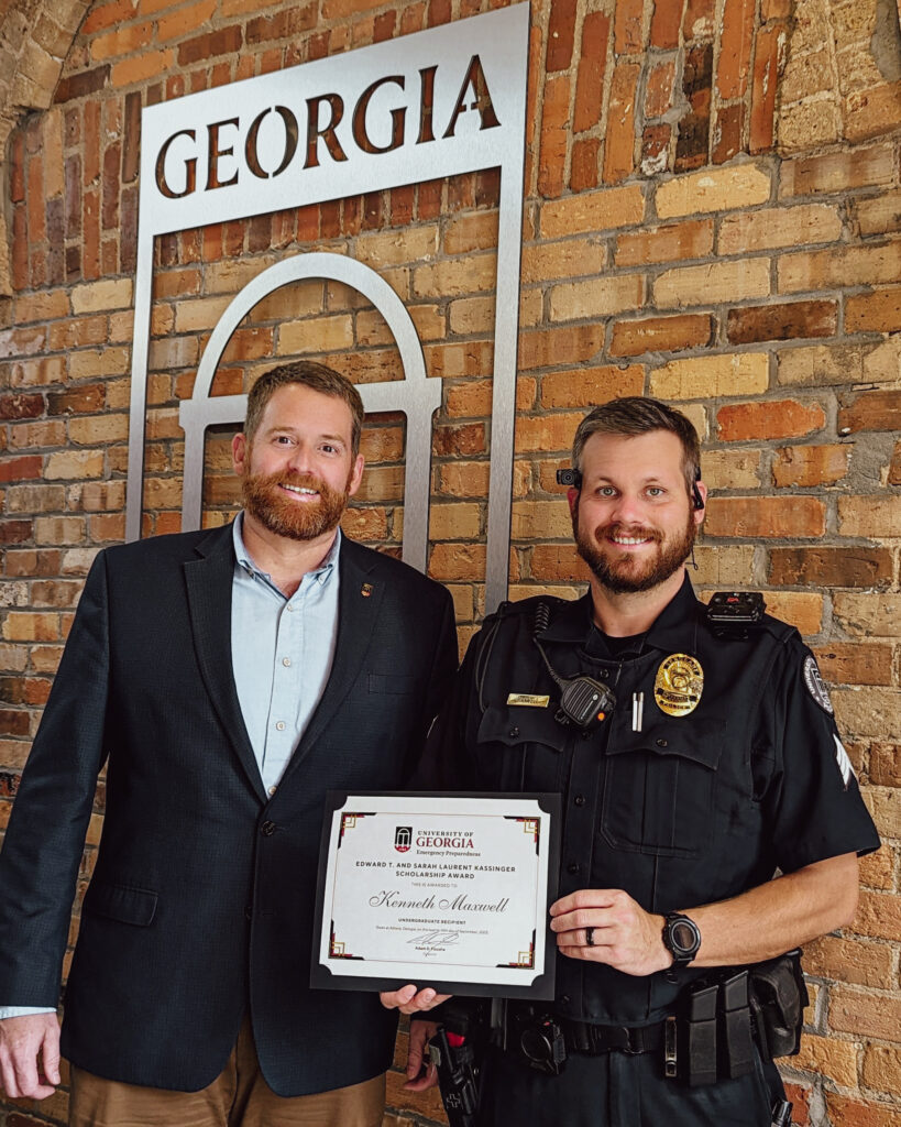 Corporal Ken Maxwell receives a certificate announcing him as the 2023 Edward T. and Sarah Laurent Kassinger Scholarship recipient from Adam Fouche, Director of the Office of Emergency Preparedness